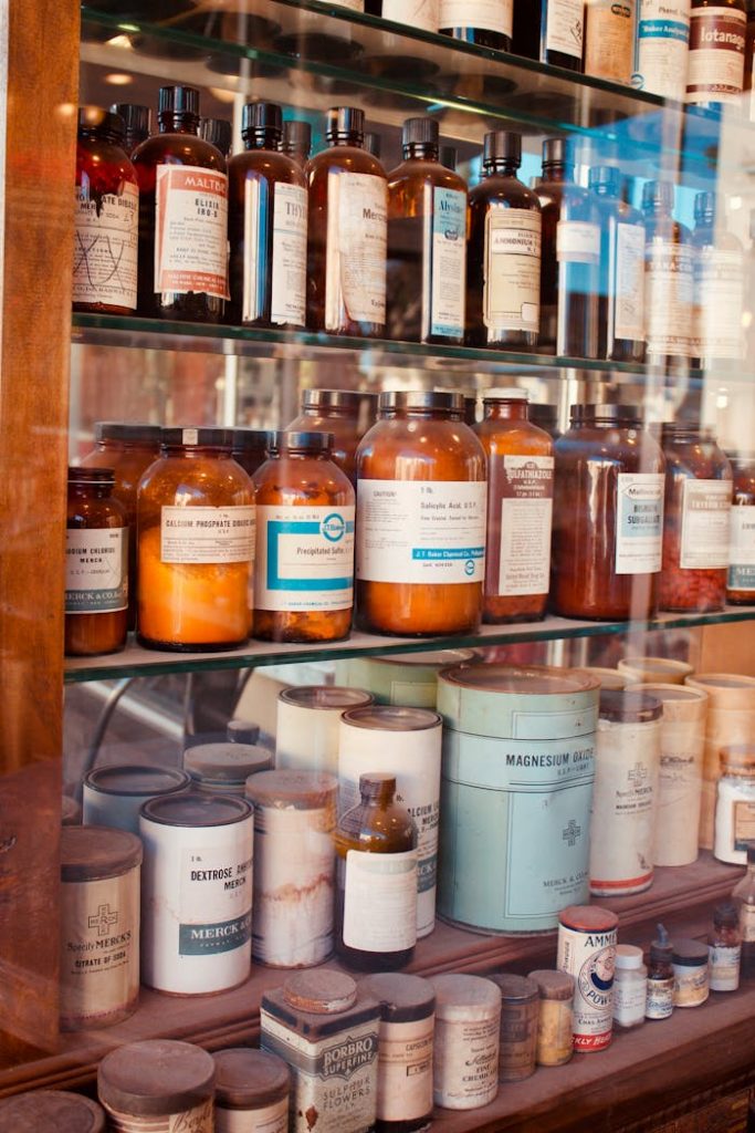 pexels photo 12494693 A collection of vintage pharmacy bottles on wooden shelves, showcasing old medicine containers.